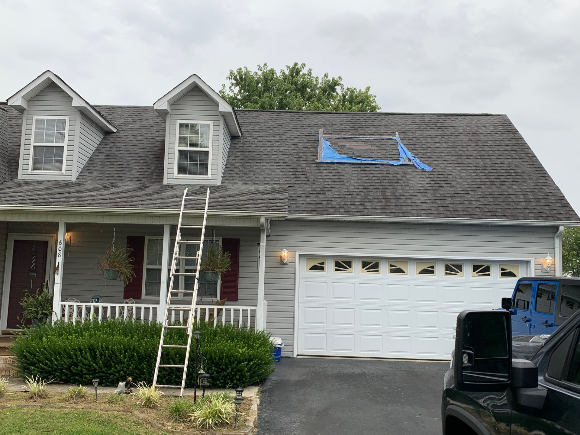 Before: shingle roof with a torn section patched by a blue tarp